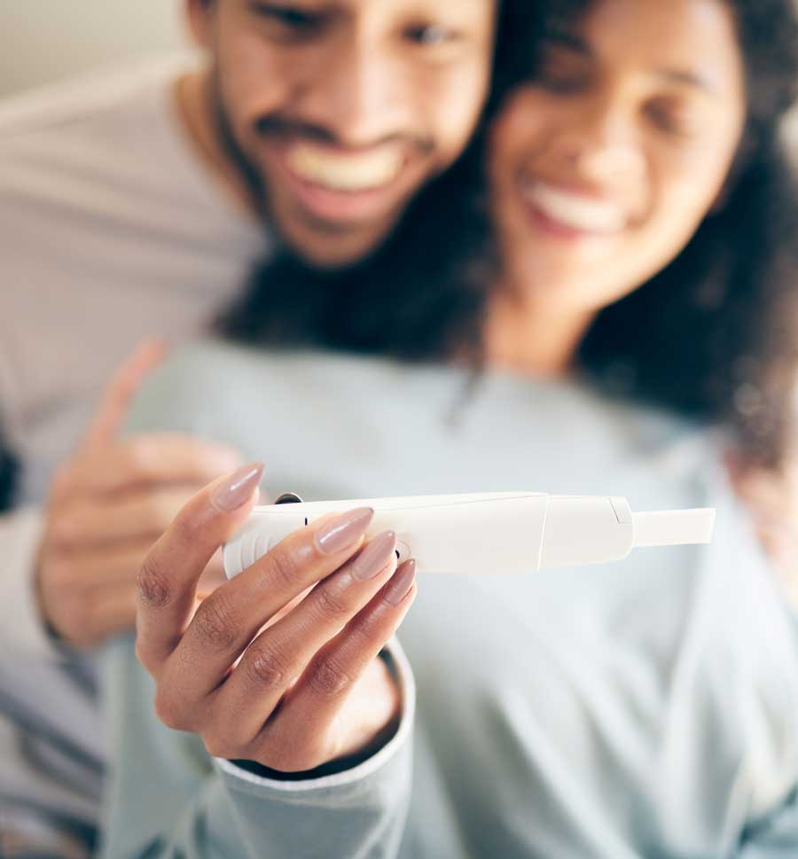 happy couple smiling and looking at a positive pregnancy test | Fertility Acupuncture Boulder & Longmont | Well Woman Acupuncture