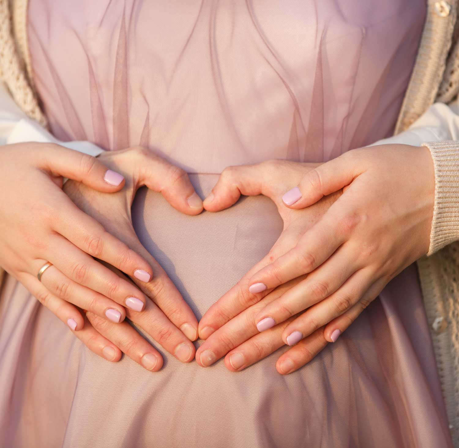 Couple holding the woman's pregnant belly with their hands in the shape of a heart | Acupuncture for IVF & IUI in Boulder & Longmont