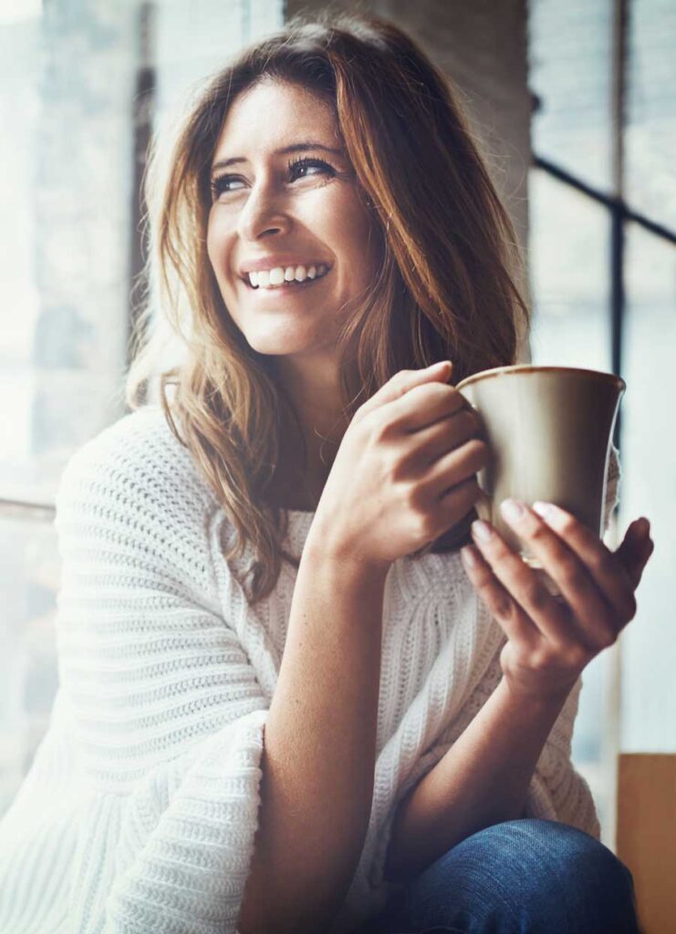 Woman smiling while holding a coffee mug | Nervous System Reset | Reset Your Nervous System Naturally