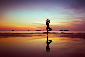 tree pose on beach at sunset